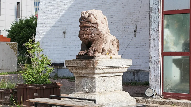 Carved stone guardian lion on a pedestal beside a doorway